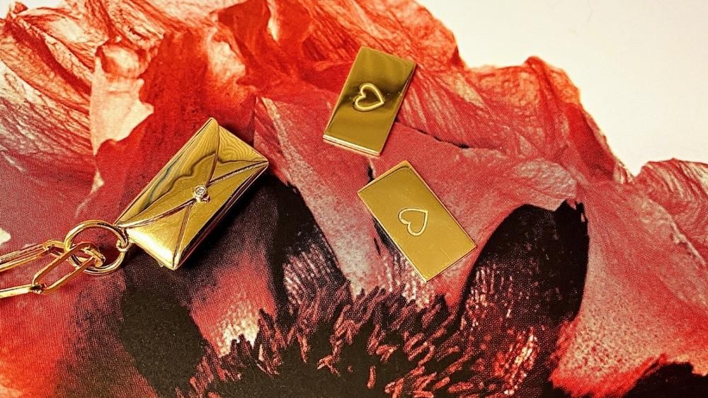 Gold love letter charm on a background of red flower petals