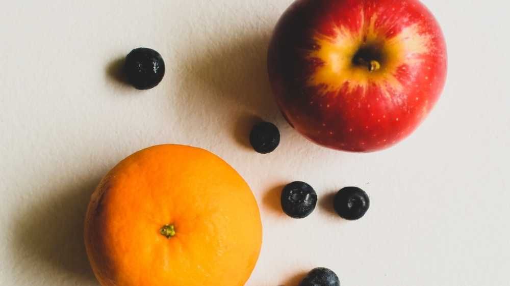 Orange and apple with some blue berries scattered