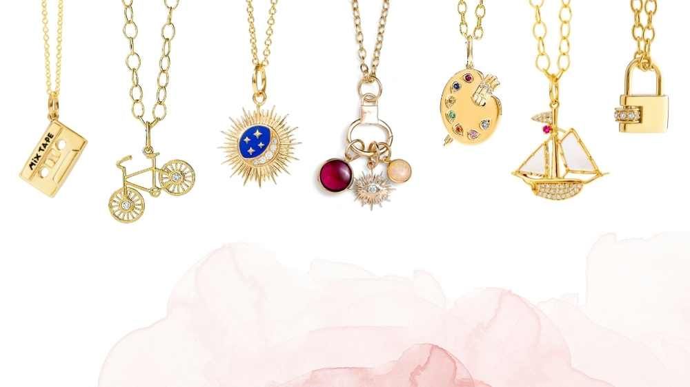 collection of little charm pendants including a mixtape, a bicycle, moon and stars pendant, chakra charms with evil eye, paint palette, carpe diem boat and gold lock pendant
